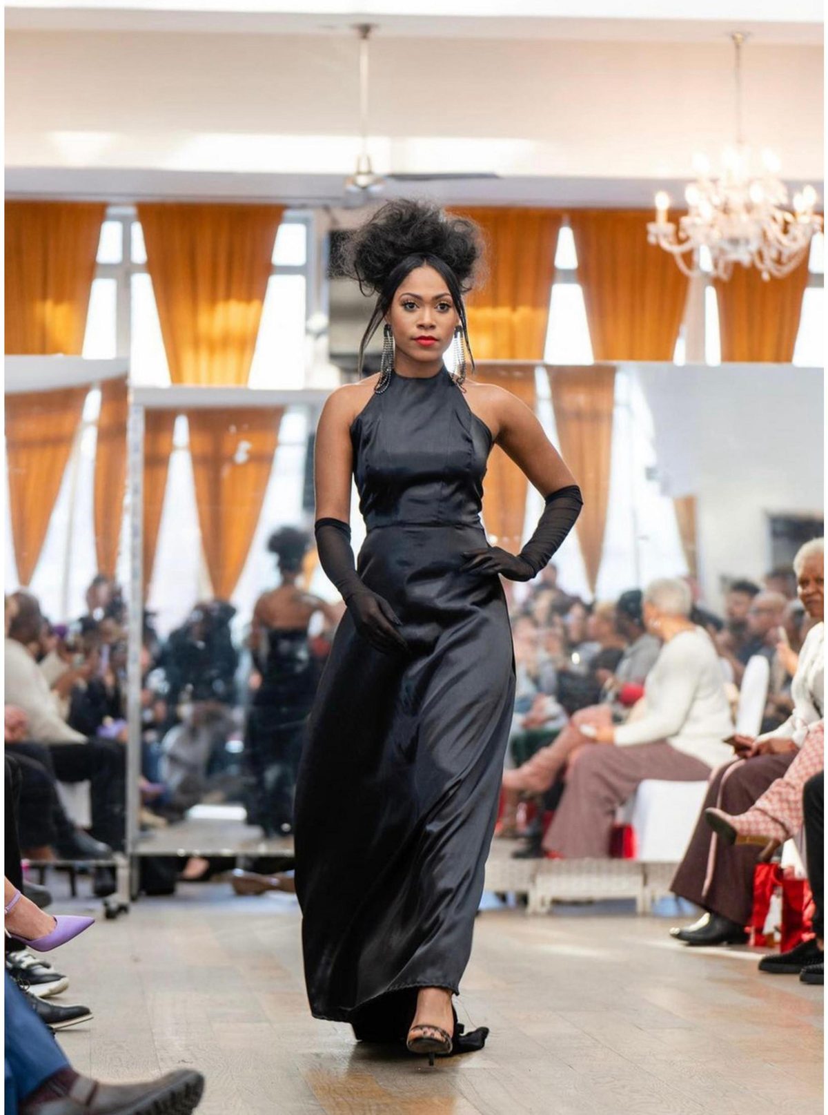 Model walking the Power Squad Campaign runway in a black evening gown.